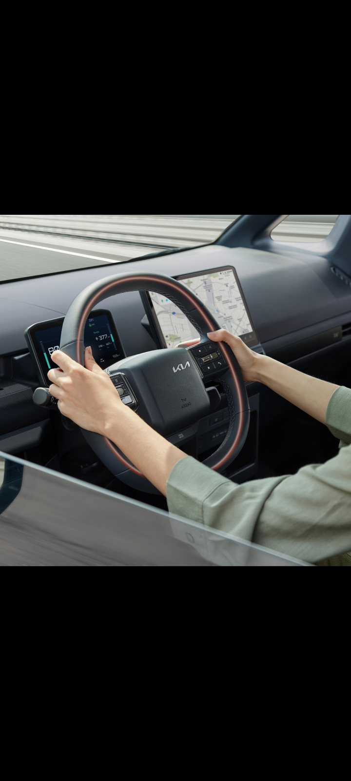 Nahaufnahme des Lenkrads im Kia PV5 Cargo mit den Händen des Fahrers.